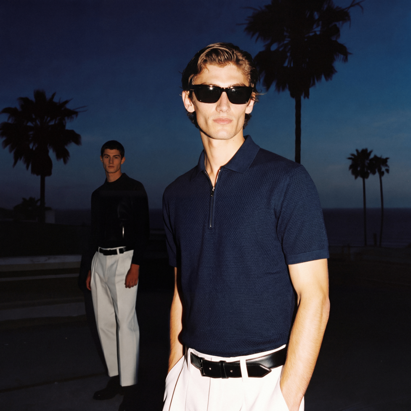 Spanish menswear: navy knit polo with white tailored trousers at dusk